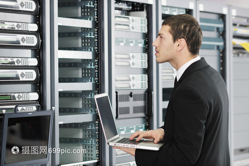 輕的IT工程師商務(wù)人員與薄的現(xiàn)代鋁筆記本電腦 網(wǎng)絡(luò)服務(wù)器機(jī)房中的高效協(xié)作